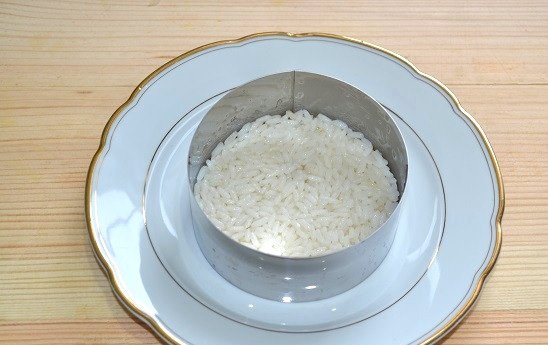 1. Этап. Салат с консервированным перцем: 4. Для сборки салата выложите на тарелку сервировочное кольцо. На дно выложите рис, разровняйте.