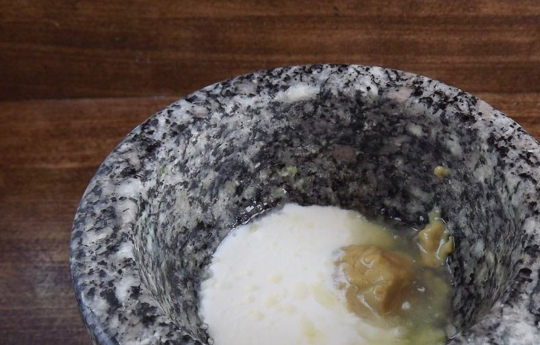 1. Этап. Салат Цезарь лучший: Пока хлеб запекается в духовке, приготовьте заправку для салата. Очистите чеснок и перетрите его в ступке с солью. Добавьте к ним сметану и горчицу.