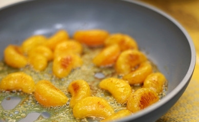 1. Этап. Кекс с мандаринами: Разогрейте на сковороде 20 г масла, добавьте чайную ложку сахара. Когда сахар растает, выложите дольки мандарина и обжарьте их по 2 минуты с каждой стороны. Затем уберите дольки на тарелку, пусть остынут.