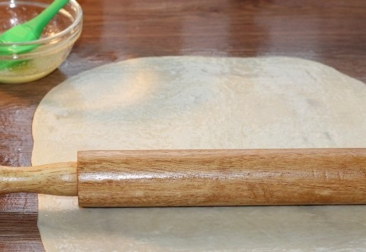 1. Этап. Лепешки по мотивам фесели: 12. Слегка смазываем столешницу растительным маслом и раскатываем все заготовки в прямоугольный пласт толщиной 1 мм. Смазываем все слои теста растопленным сливочным маслом.