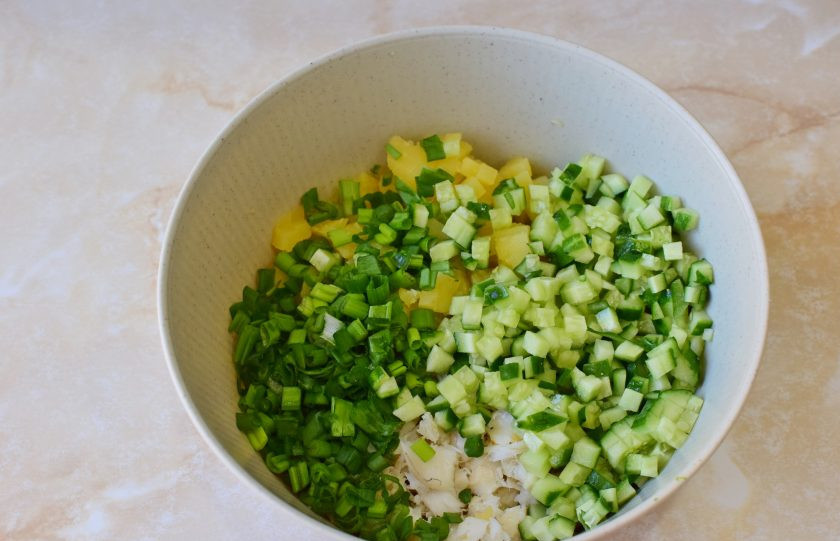 1. Этап. Салат с треской и огурцом: Следом нарежьте огурец и зеленый лук. Добавьте их к салату.