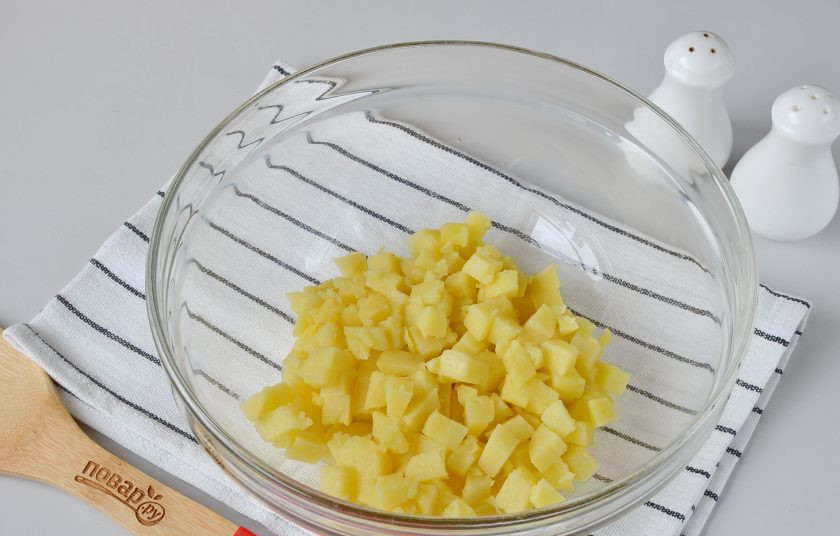 1. Этап. Салат с копченой рыбой: Нарежьте остывший картофель кубиками небольшого размера. Выложите в большой салатник.