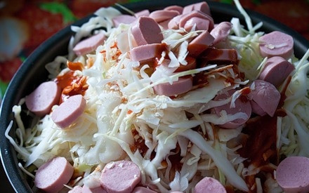 1. Этап. Тушеная капуста с сосиской: 1. На дно чаши мультиварки налейте немного растительного масла. Нашинкуйте капусту, нарежьте кружочками сосиски. Томатную пасту разведите водой, добавьте соль и перец по вкусу. Все выложите в чашу.