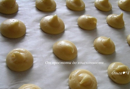 1. Этап. Апельсиновые профитроли: Заполните заварным тестом кондитерский шприц с круглой насадкой и отсадите на выстеленный бумагой для выпечки противень около 20 шариков одинакового размера.