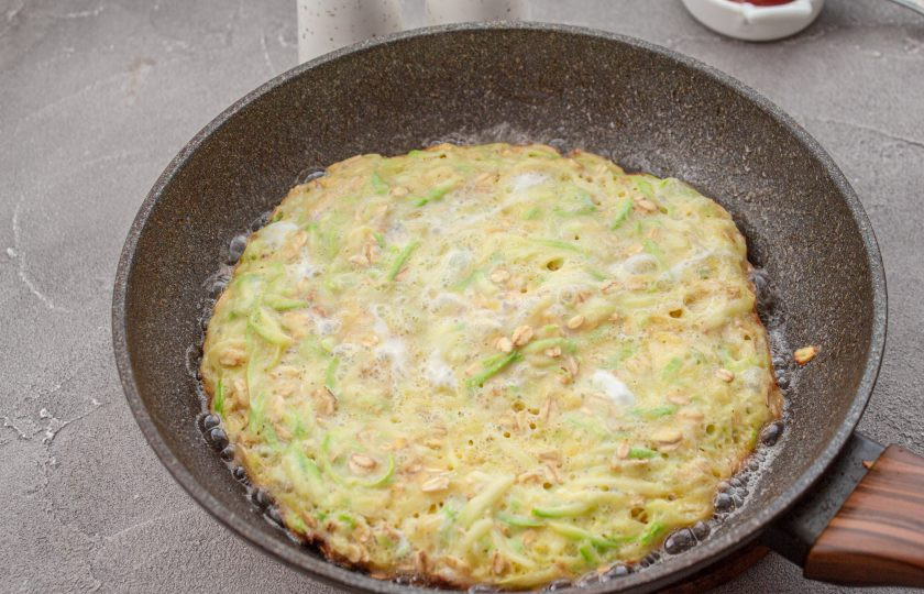 1. Этап. Пицца из кабачков без муки на сковороде: Кабачковое тесто выложите в хорошо разогретую сковороду с маслом и жарьте при небольшом нагреве, до румяности с одной стороны.