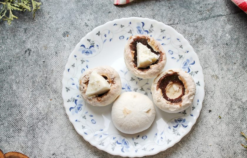 1. Этап. Шампиньоны с куриным фаршем в духовке: У шампиньонов удалите ножки и снимите верхний слой с шампиньонов. Внутри грибы посолите и смажьте растительным маслом. Сыр разрежьте на четыре части и положите внутрь шампиньонов.