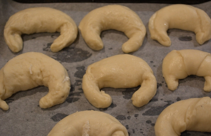 1. Этап. Рожки с творогом в духовке: Готовые изделия уложите на противень. Я его застелила бумагой для выпечки. Каждый рожок надо смазать взбитым яйцом, но лучше чистым желтком. Именно от желтка они получаются такие яркие сверху.