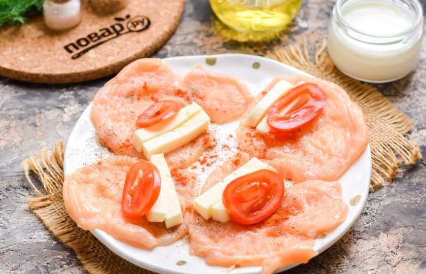 1. Этап. Куриные рулетики с моцареллой: Сыр нарежьте полосками и выложите на край каждой отбивной. Рядом с сыром выложите нарезанные дольки помидоров.