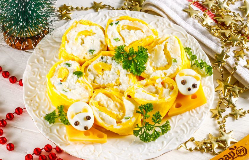 1. Этап. Рулет на год Крысы: Сделайте в сырных ломтиках отверстия с помощью соломинки с широким отверстием. Из кусочков отверстий создайте ушки мышкам из отварных перепелиных яиц, надрезав их ножом. Глазки и нос - из горошин черного перца. Украсьте ими салат и подайте к столу.