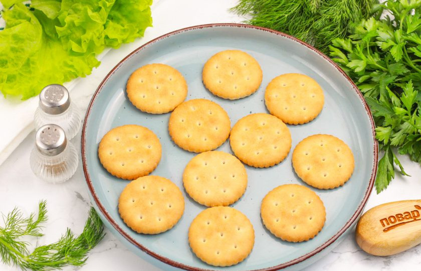 1. Этап. Канапе на крекерах на праздничный стол: Выложите крекеры на тарелку или блюдо. Они будут являться хлебной основой для будущих канапе.