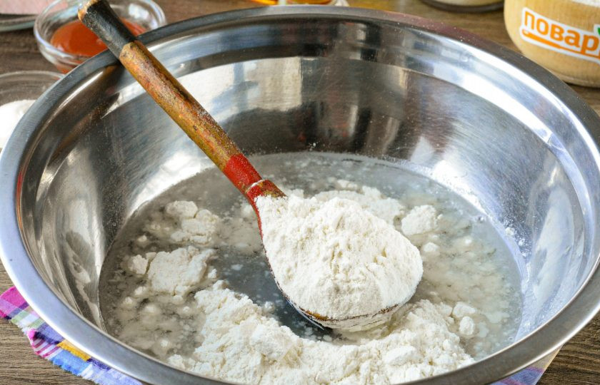 1. Этап. Пицца в чебуреке: Всыпьте половину порции муки и тщательно перемешайте тесто, чтобы не было комочков.