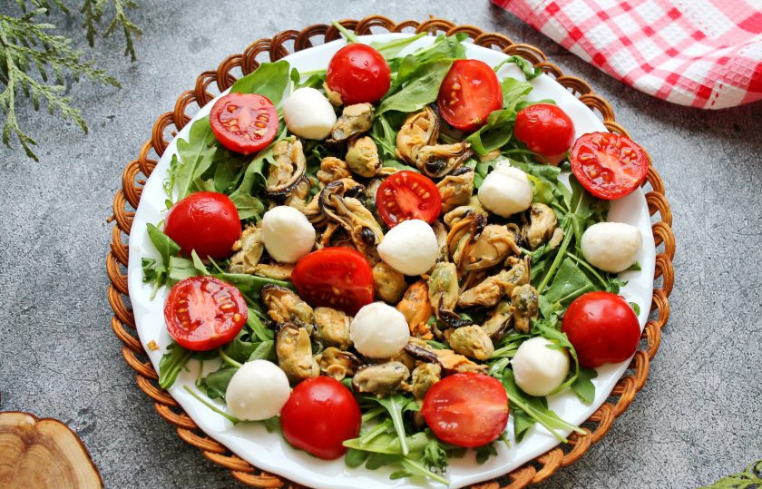 1. Этап. Салат с мидиями, моцареллой и рукколой: Шарики моцареллы разрежьте пополам или просто целыми разложите на салат. Смешайте растительное масло, сок лимона, соль и перец. Перелейте в соусник и сразу подавайте с салатом из мидий, моцареллы и рукколы на стол.