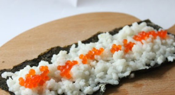 1. Этап. Роллы с красной икрой: Выкладываем на рис часть икры.