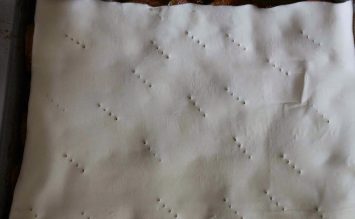 1. Этап. Пирог из апельсинов: Перекладываем апельсиновую массу с карамелью в форму для выпечки, смазанную маслом. Ставим в духовку на 20 минут, затем извлекаем и накрываем подходящим по размеру кусочком слоеного теста. В тесте делаем проколы вилкой. Возвращаем пирог в духовку еще на 10 минут.