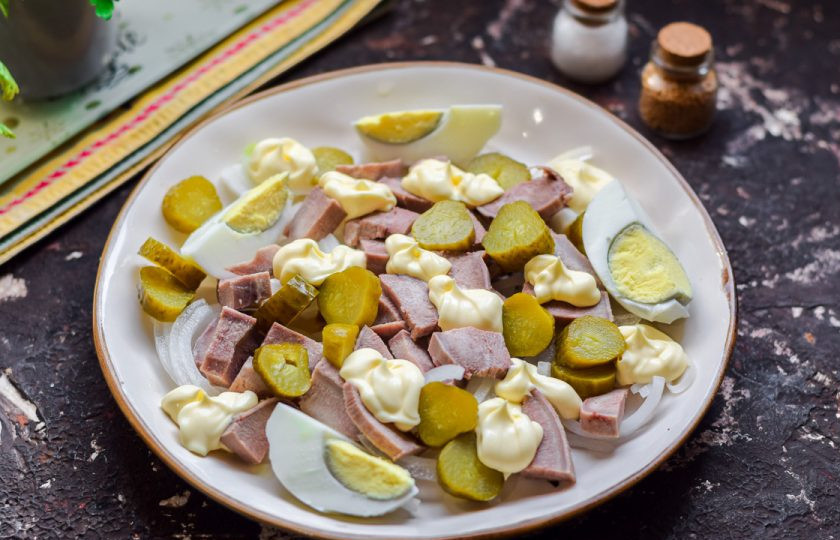 1. Этап. Салат с языком и маринованным луком: Маринованные огурцы нарежьте кружочками или кубиками, переложите в салат. Отварите заранее куриное яйцо – 10 минут в подсоленной воде будет достаточно. Очистите яйцо и нарежьте на 4 части, разложите на тарелке. Добавьте в салат майонез, соль и перец. Подавайте к столу.