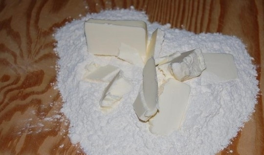 1. Этап. Сладкий пирог на День Святого Валентина: 1. В миске или на разделочной доске перетрите руками кубики холодного сливочного масла с просеянной мукой, пока не получится мучная крошка.