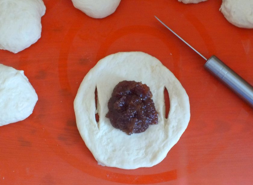 1. Этап. Бабушкины булочки: На лепешку из теста выложите 1,5 ст.л. густого повидла. Немного размажьте его. От края лепешки отступите 3-4 см. и сделайте разрез, повторите с другой стороны.