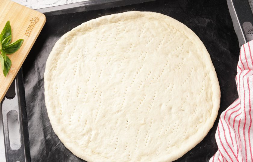 1. Этап. Пицца Нью-йорк: Из теста для пиццы на присыпанной мукой рабочей поверхности раскатайте круг диаметром около 30 см. и толщиной около 5-6 мм. Переложите на противень и руками сформируйте бортики, дно наколите вилкой.