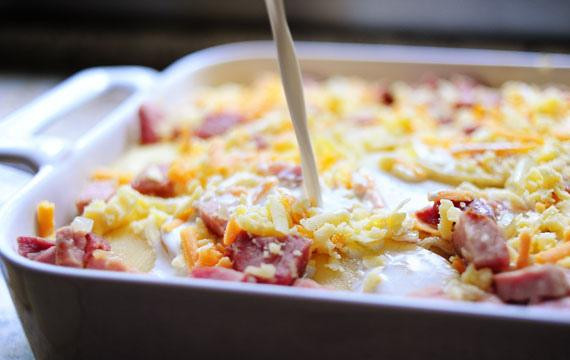 1. Этап. Запеченный картофель с ветчиной: 6. Посыпать 1/3 смеси лука и ветчины, затем посыпать 1/3 сыра и влить 1/3 сливочной смеси. Повторить слои еще 2 раза, закончив сыром и полив оставшейся сливочной смесью.