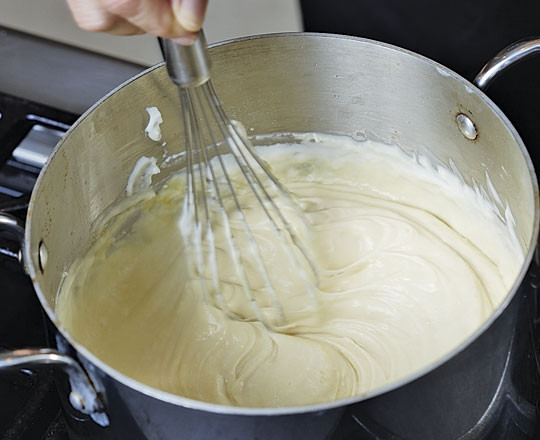 1. Этап. Мусака с баклажанами и картофелем: 5. Последний подготовительный этап — это соус. Для его приготовления в сотейнике доведите до кипения молоко. Отдельно на сковороде растопите сливочное масло. Всыпьте муку и тщательно перемешайте, чтобы не было комочков. Когда мука станет золотистой, переложите ее в молоко. Добавьте соль, перец, мускатный орех и снимите с огня. Остудите немного, а после добавьте взбитые яйца и тертый сыр. Продолжайте взбивать, пока соус не станет полностью однородным.