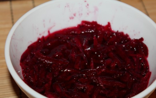 1. Этап. Закуска Клубничка: 3. Натрите на терке свеклу, выложите её в глубокую мисочку. Добавьте воду и сок лимона. Аккуратно перемешайте. Отправьте мисочку в микроволновку на 5 минут, установив максимальную мощность. После остудите свеклу, откиньте её на дуршлаг, сохранив при этом сок.