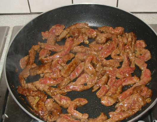 1. Этап. Тайская зажарка: 3. Нарезать тонко красный перец. Разогреть масло в сковородке, добавить говядину, миндаль и мелко нарезанный чеснок, хорошо перемешать и готовить 4 минуты, пока мясо не станет золотисто-коричневого оттенка.