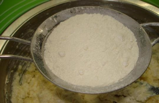 1. Этап. Творожно-песочное тесто: 4. И последним ингредиентом, который необходим, будет мука. Ее нужно просеивать маленькими порциями, постоянно перемешивая. На определенном этапе творожно-песочное тесто в домашних условиях нужно замешивать уже на рабочей поверхности.