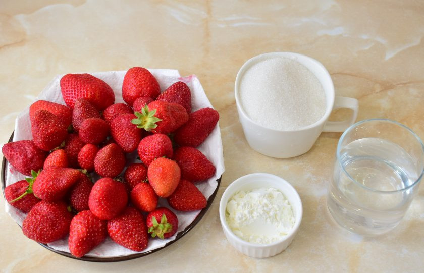 1. Этап. Варенье из клубники с кукурузным крахмалом: Для приготовления варенья подготовьте необходимые ингредиенты. Ягоды промойте от загрязнений и удалите плодоножку. Теперь отмерьте нужное количество ягод.