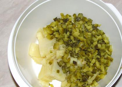 1. Этап. Салат с колбасой и яйцами: Кладем в салатницу нарезанные картофель и огурцы.