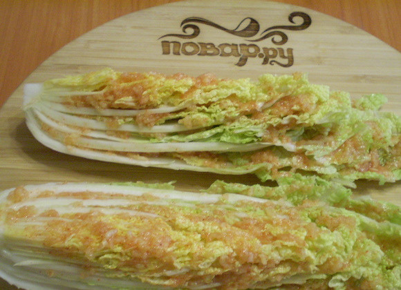 1. Этап. Засолка пекинской капусты по-корейски: Натрите капустные листья полученной кашицей. Сложите их в кастрюлю, поставьте гнет. Оставьте на 8-10 часов для засолки. Через 10 часов порежьте кусочками и подавайте на стол.