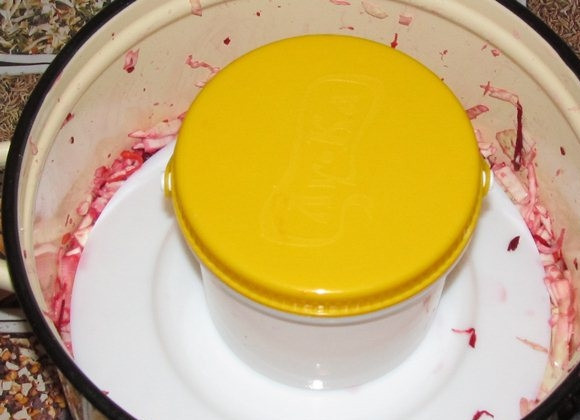 1. Этап. Капуста, квашенная со свеклой: 5. Выложите капусту в бочонок (или другую емкость для сквашивания). Уплотните, накройте тарелкой и установите сверху банку с водой. Оставьте при комнатной температуре на 2.5-3 дня.