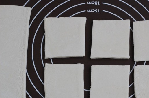 1. Этап. Ленивые мини пирожки с индейкой: Слоеное тесто раскатайте в прямоугольный пласт и нарежьте на квадратики. У меня получились квадратики где то размером 8*8 см.