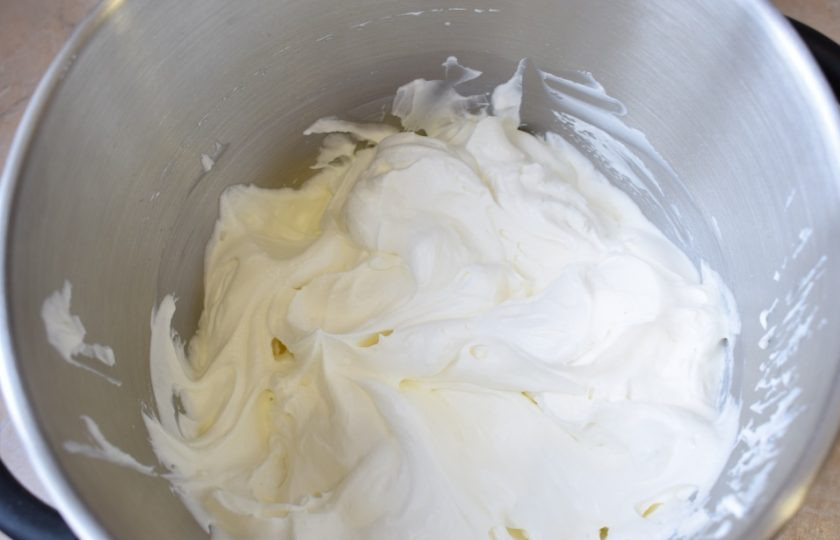 1. Этап. Бисквитный торт с крем-чизом: Для приготовления крема взбейте сливки с сахарной пудрой в устойчивый крем. Отложите немного крема для внешней поверхности торта.