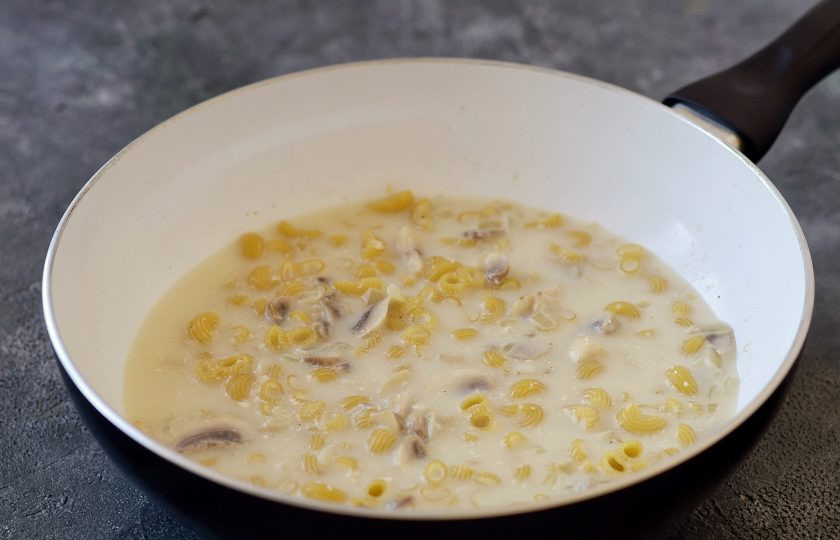 1. Этап. Постная паста с грибами: Насыпьте в сковороду макароны. Долейте воду, чтобы она полностью их покрывала. Накройте крышкой и готовьте 6-7 минут.