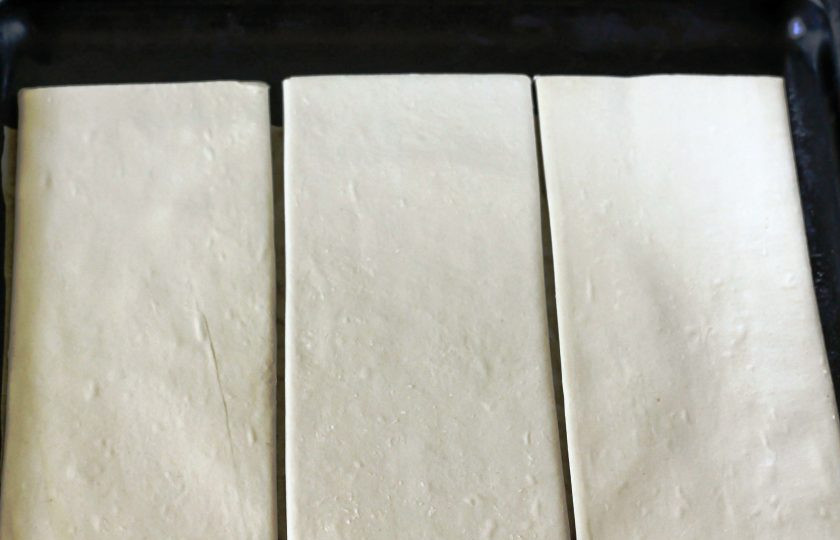 1. Этап. Ленивый Наполеон из слоеного теста: Слоеное тесто слегка разморозьте и выложите на противень. Разогрейте духовку до 200 градусов и запеките листы теста до румяности примерно 20 минут.