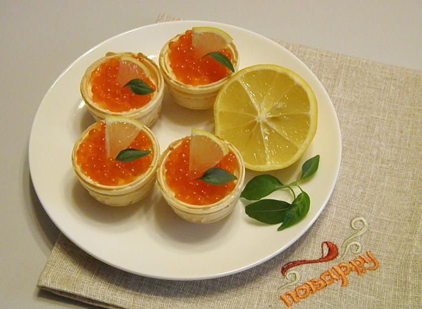 1. Этап. Тарталетки с красной икрой: Украсьте тарталетки с икрой ломтиком лимона и зеленью. Подавайте закуску к столу охлажденной.