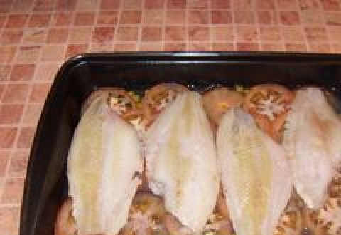 1. Этап. Камбала в духовке с картошкой: Камбалу солим и перчим, выкладываем на помидоры.