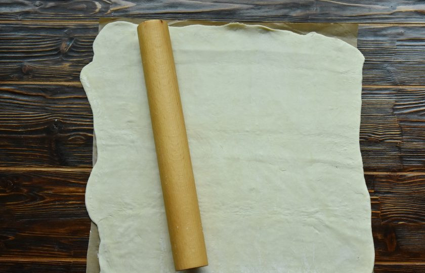 1. Этап. Штрудель с вишневой начинкой классический: Слоеное тесто заранее извлеките из холодильника, чтобы оно разморозилось. Раскатайте тесто в пласт прямоугольной формы, толщиной около 3 мм. Удобнее формировать штрудель сразу на пергаментной бумаге. С ее помощью можно свернуть рулет и переместить на ней же изделие на противень.