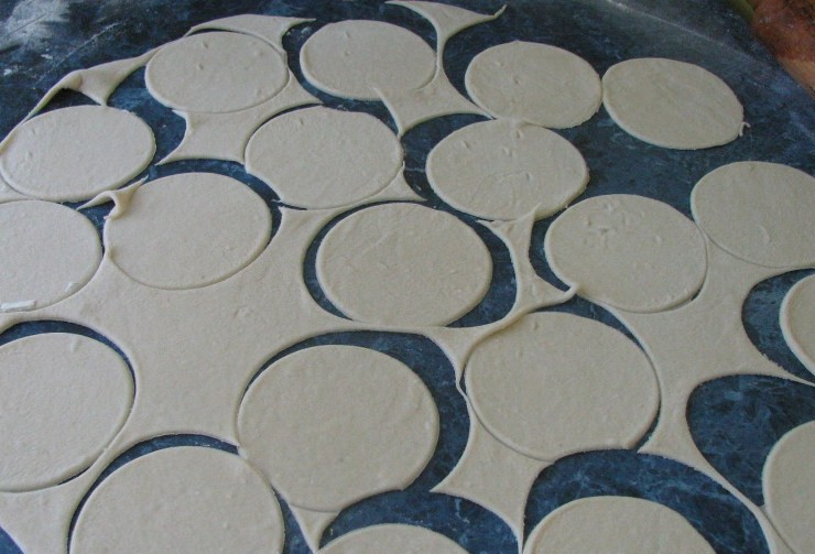 1. Этап. Вареники с малиной: Для теста смешиваем в миске кефир с содой и солью, затем начинаем постепенно всыпать в кефир муку и замешивать тесто. Количество муки здесь написано приблизительно, ее нужно добавлять до тех пор, пока у нас не получится мягкое, однородное, эластичное и не прилипающее к рукам тесто. Накрываем его полотенцем и также на 20-30 минут оставляем отдыхать. Когда и тесто и малина будут готовы, разделяем тесто на несколько частей и раскатываем поочередно каждую в пласт, вырезаем из теста кружочки.