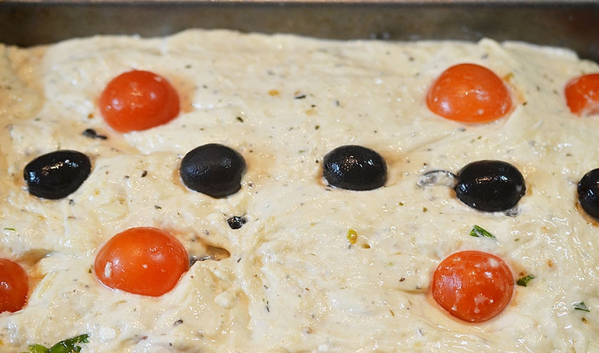 1. Этап. Сырный хлеб с маслинами и помидорами черри: Выложите тесто в форму для кекса, предварительно смазанную маслом. Украсьте маслинами и черри.