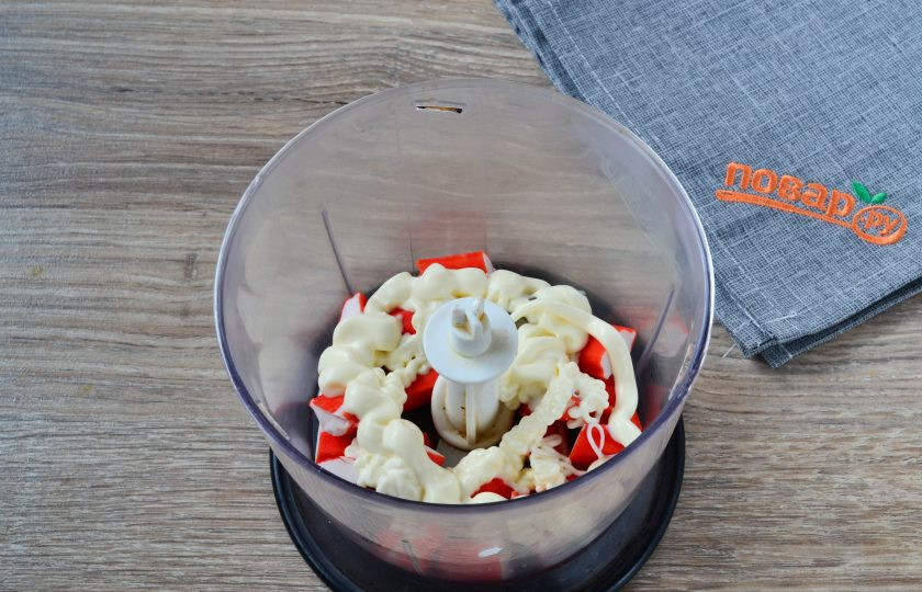 1. Этап. Закусочный торт с крабовой начинкой: Крабовые палочки порежьте небольшими кусками и сложите в чашу блендера, туда же добавьте 1 ст. ложку (или чуть больше) сметаны или майонеза (я использую майонез). Измельчите крабовые палочки до состояния кашицы или чуть крупнее, как вам больше нравится.