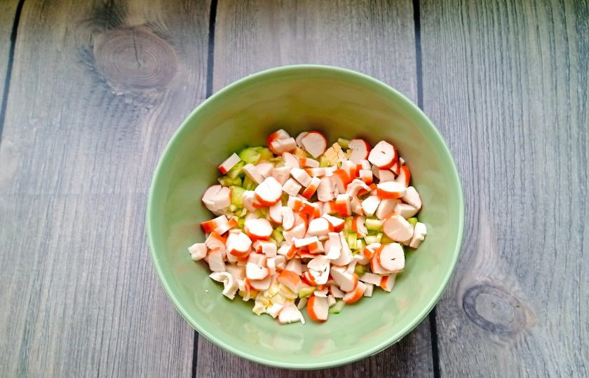 1. Этап. Салат из крабовых палочек с луком и зеленью: Крабовые палочки нарежьте кубиками и добавьте в салат.