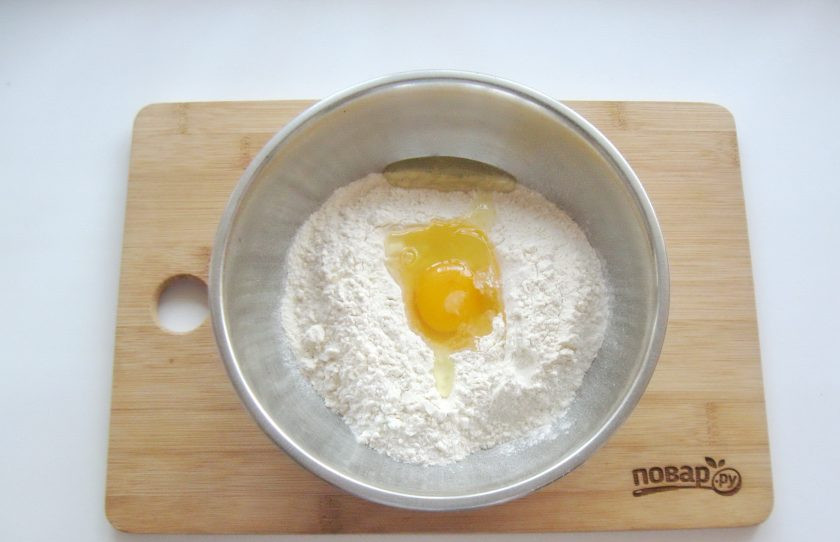 1. Этап. Вареники на минеральной воде: Разбейте в муку яйцо.