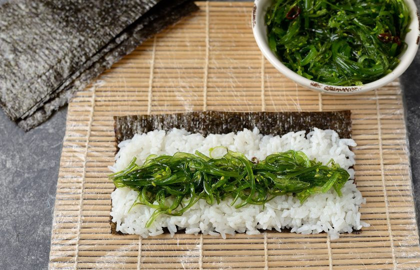 1. Этап. Роллы с чукой: Откройте упаковку с чука, их нужно тщательно отжать от маринада и масла. Выложите посередине риса немного водорослей.