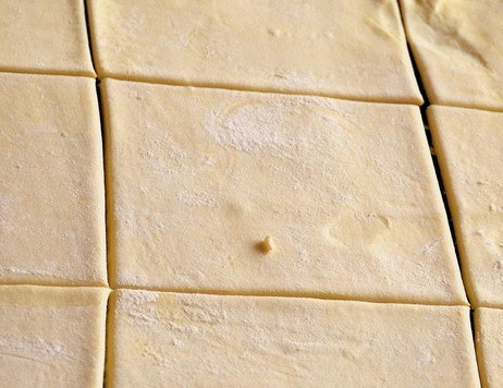 1. Этап. Слойки с яблоками и миндалем: Слоеное тесто немного раскатать, разрезать на 12 квадратов и уложить их в форму для маффинов, предварительно смазанную растительным маслом.