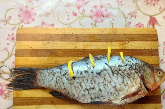 1. Этап. Карась в фольге в духовке: 6. Сверху сделайте несколько неглубоких надрезов и поместите туда лимон. Остатками сока можно полить карася сверху.