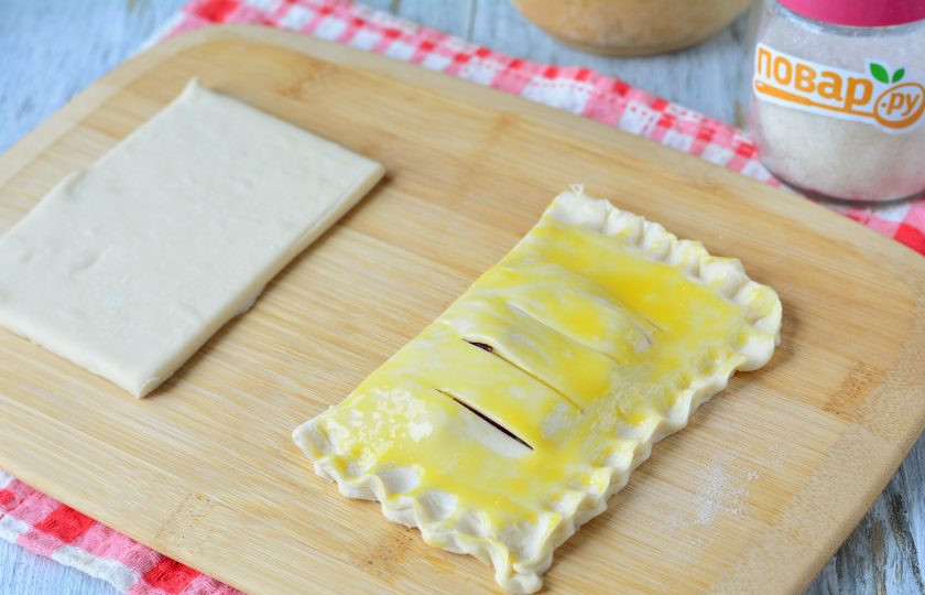 1. Этап. Слойки из слоеного теста с клюквой: Смажьте слойки яйцом.