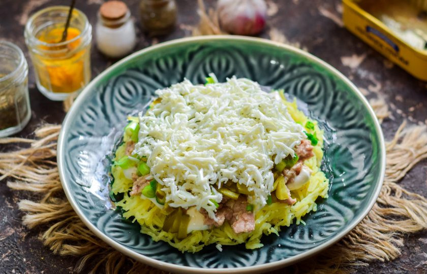 1. Этап. Салат из печени трески слоеный: Куриные яйца разделите на желтки и белки. Белки натрите мелкой стружкой, уложите поверх огурцов, смажьте немного майонезом.