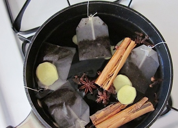 1. Этап. Праздничный чай: 1. В кастрюлю налейте воду, добавьте пакетики чая, ломтики очищенного корня имбиря, палочки корицы и гвоздики, а также анис. Доведите все содержимое до кипения, затем уменьшите огонь и кипятите 5 минут под закрытой крышкой.