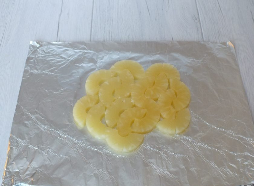 1. Этап. Горбуша с ананасами в духовке: Возьмите фольгу. Отрежьте лист длиной 35 см. Кольца ананаса разрежьте пополам и выложите на лист фольги, чтобы половинки соприкасались между собой как можно больше.